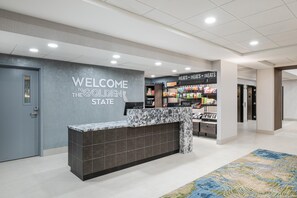 Een hotel receptie met een marmeren balie, een welkom bord en een presentatie van snacks.