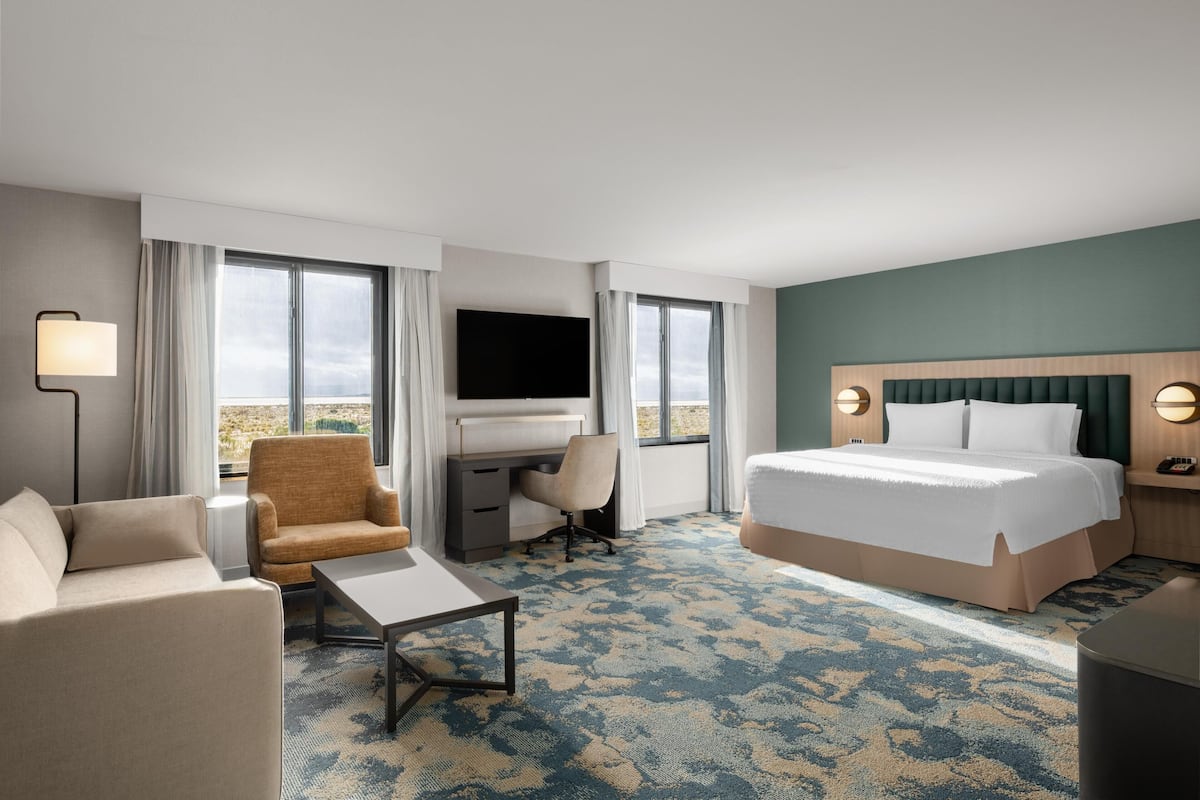 Een hotelkamer met een bed, een bureau, een stoel, een bank, een televisie en een raam.