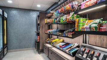 A snack aisle with various packaged snacks and a refrigerated section with wine bottles.