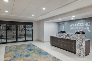 A hotel reception area with a marble counter, a welcome sign, and a patterned rug.