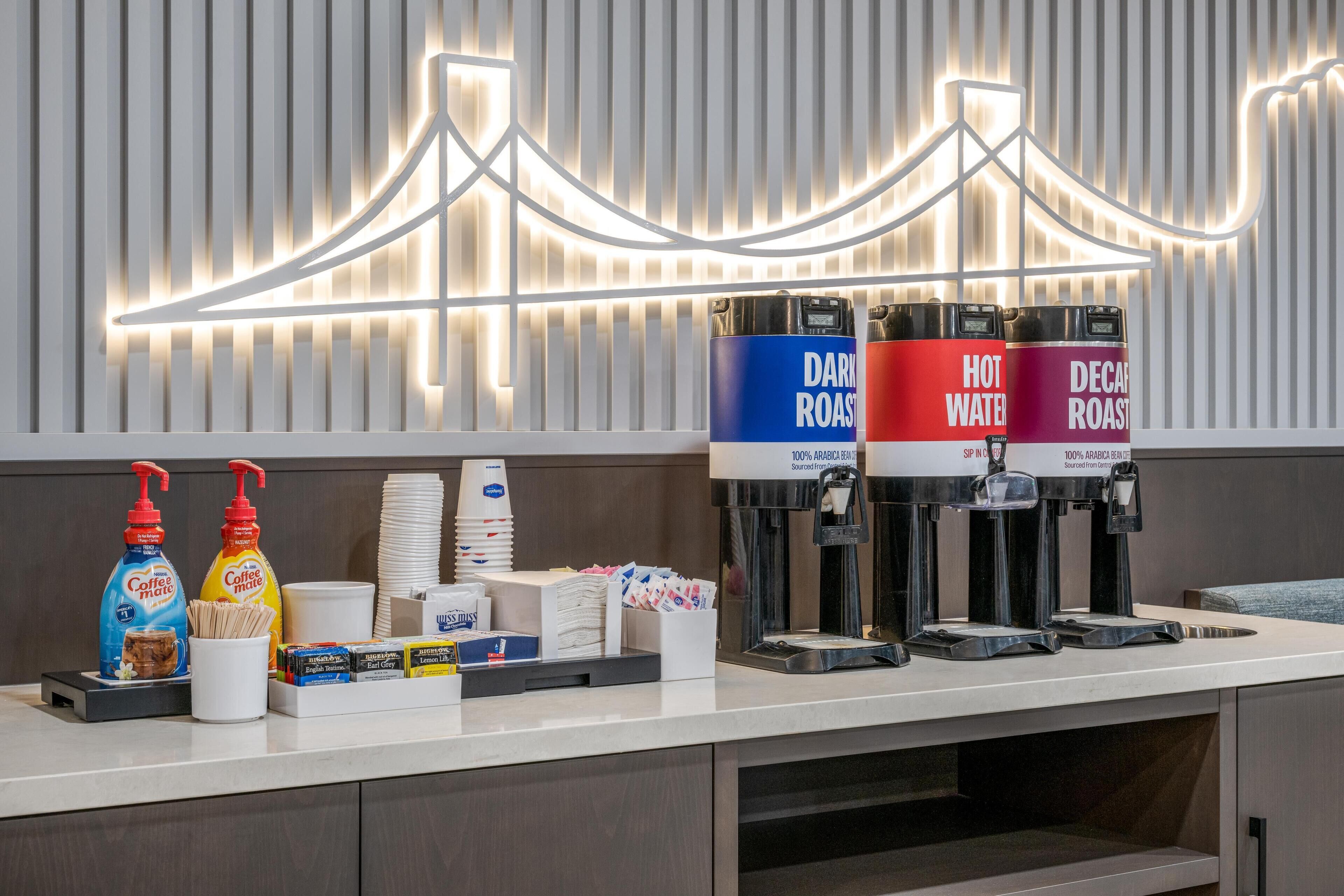 A coffee station with three dispensers labeled 'Dark Roast,' 'Hot Water,' and 'Decaf Roast.'