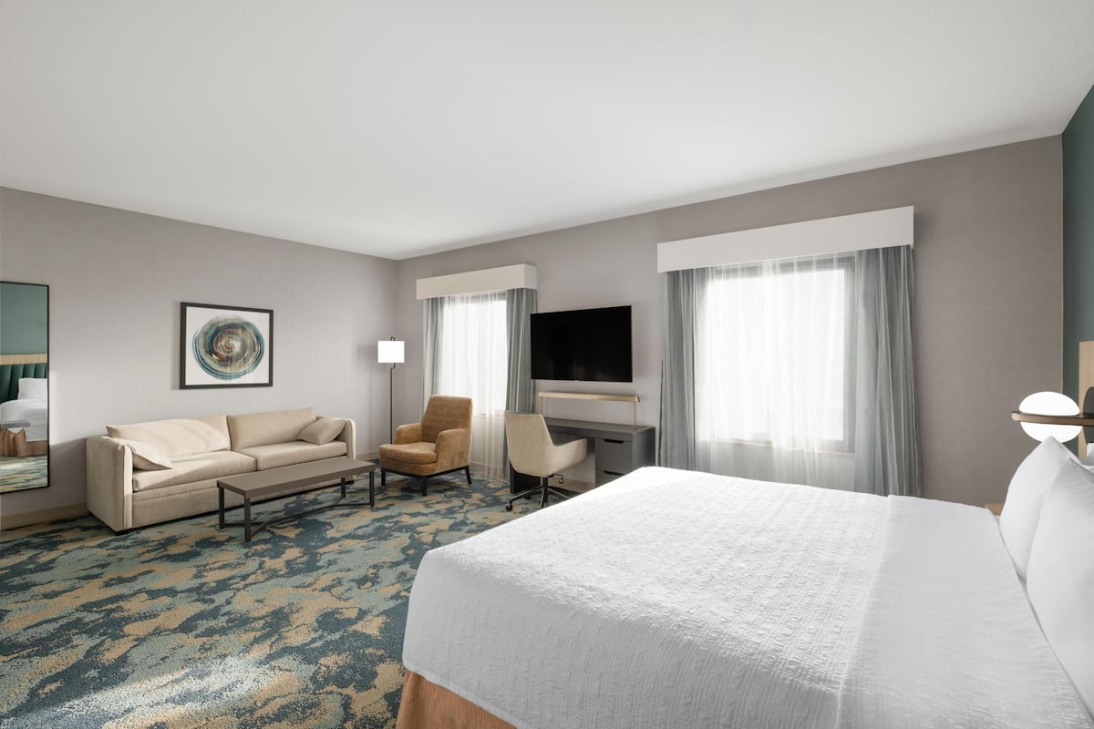 Een hotelkamer met een bed, een bureau, een stoel, een bank en een televisie.