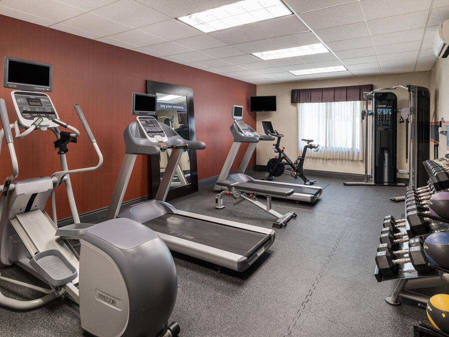 A fitness center with treadmills, an elliptical, a stationary bike, and free weights.