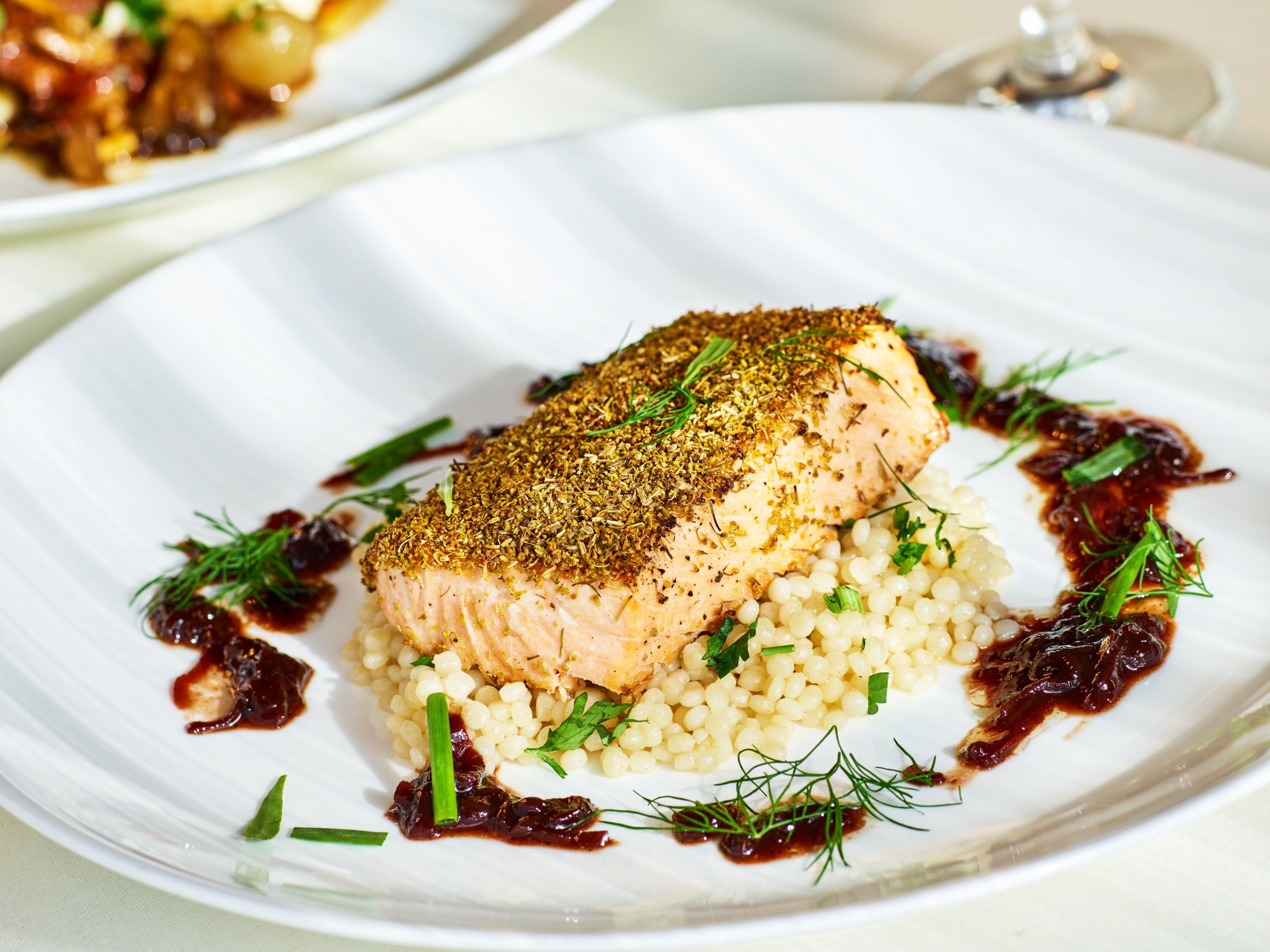 A plate with a piece of salmon, rice, and garnishes.