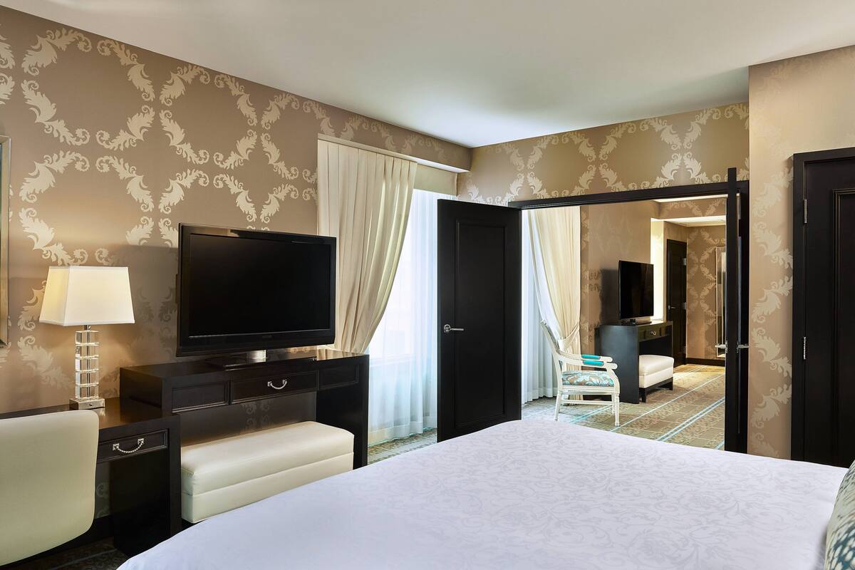 A hotel room with a bed, a TV, a desk, and a chair.