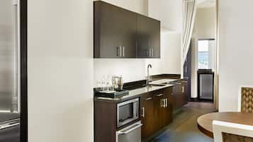 A modern kitchen with dark cabinets, stainless steel appliances, and a large window with a view.