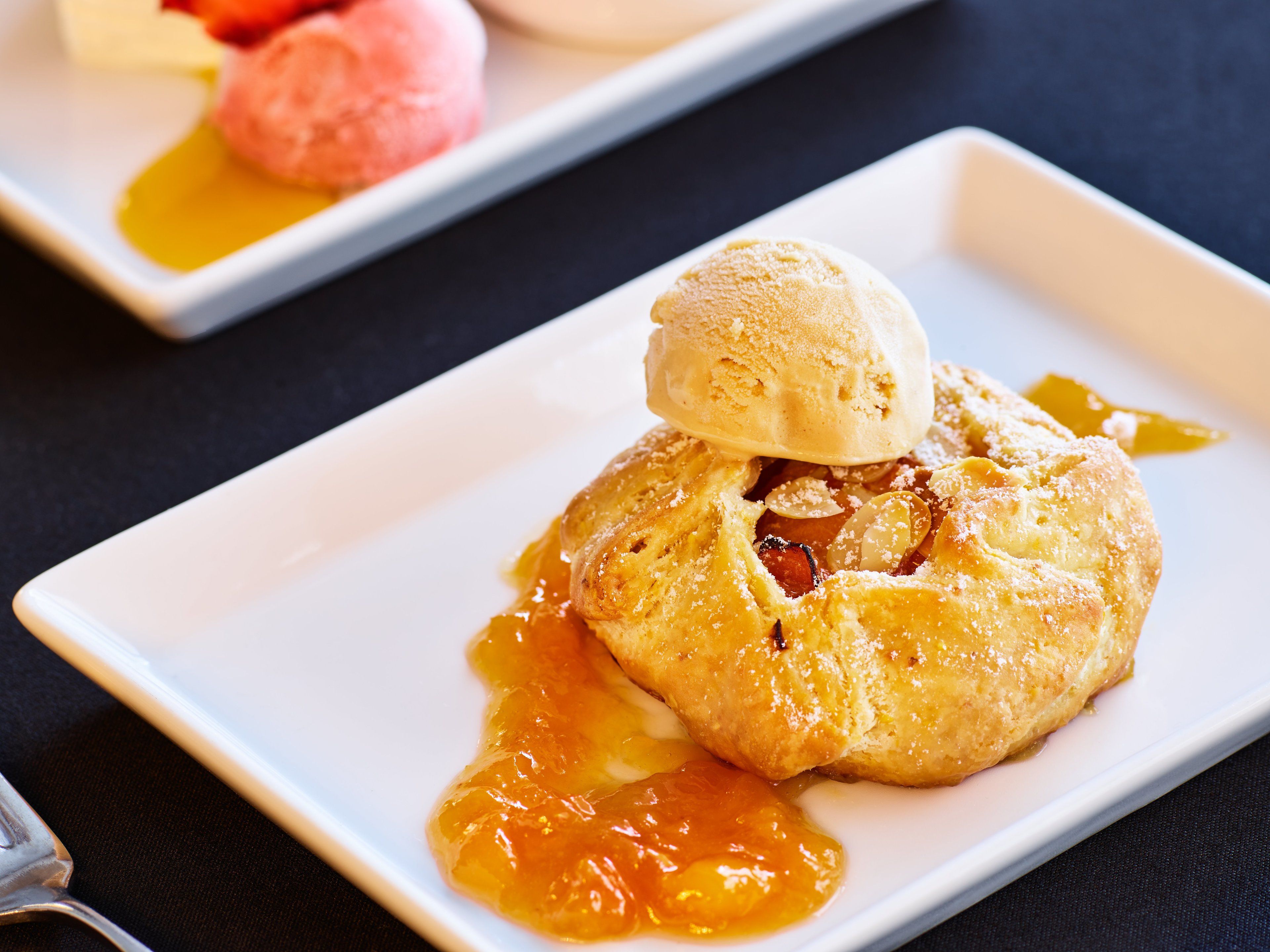 A dessert with a scoop of ice cream on top of a pastry, served on a white plate.