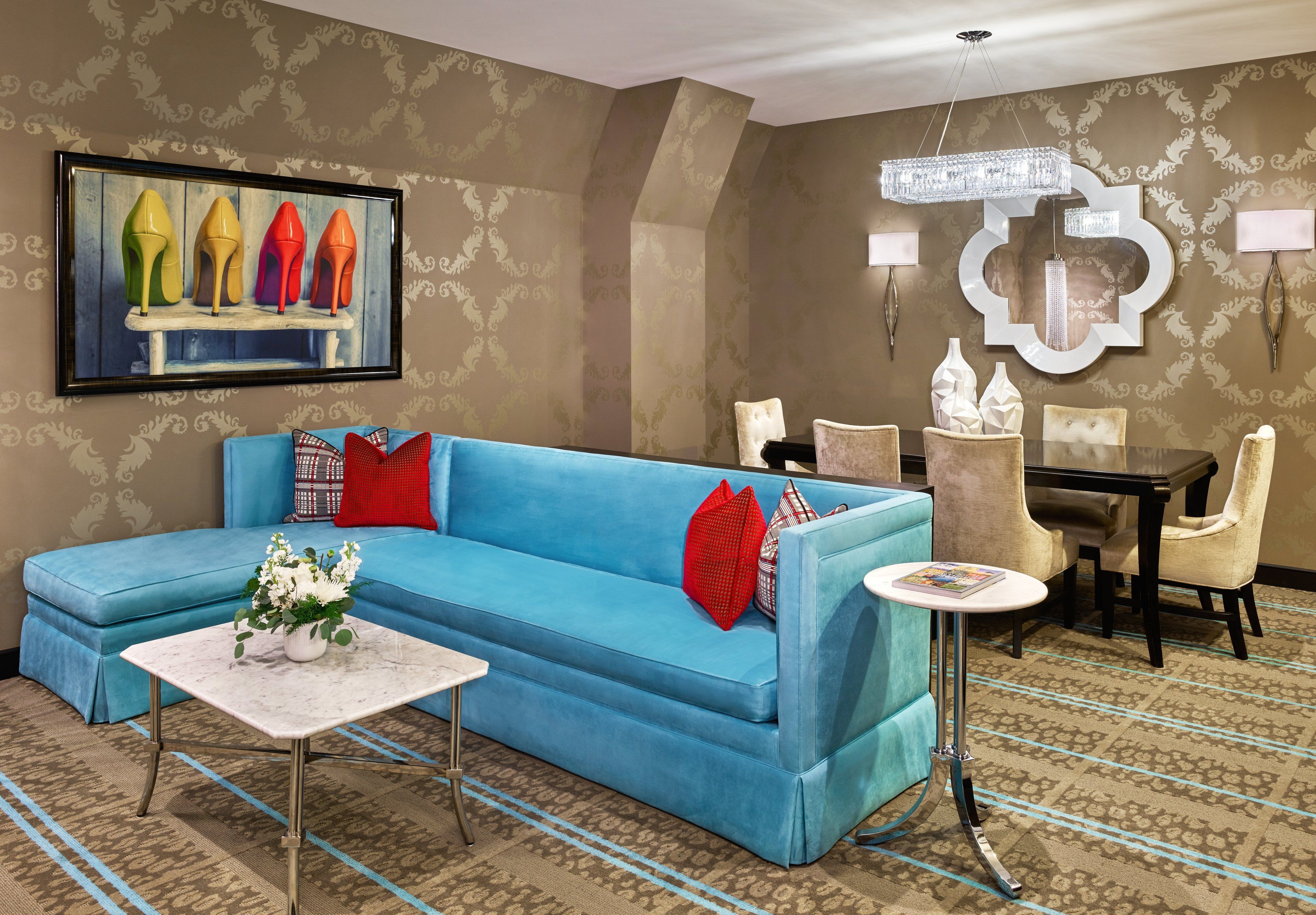 A living room with a blue sofa, a small table with a vase of flowers, and a dining area with chairs and a table.