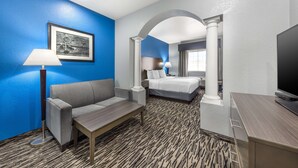 Une chambre d’hôtel avec un mur d’accent bleu, un lit avec une literie blanche, un bureau avec une télévision et une moquette à motifs.