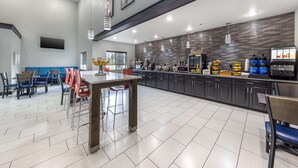 Une cuisine moderne dotée d’un coin bar, comprenant un grand îlot central, des tabourets de bar et divers appareils de cuisine.