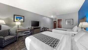 A hotel room with two beds, a desk, a television, and a chair.
