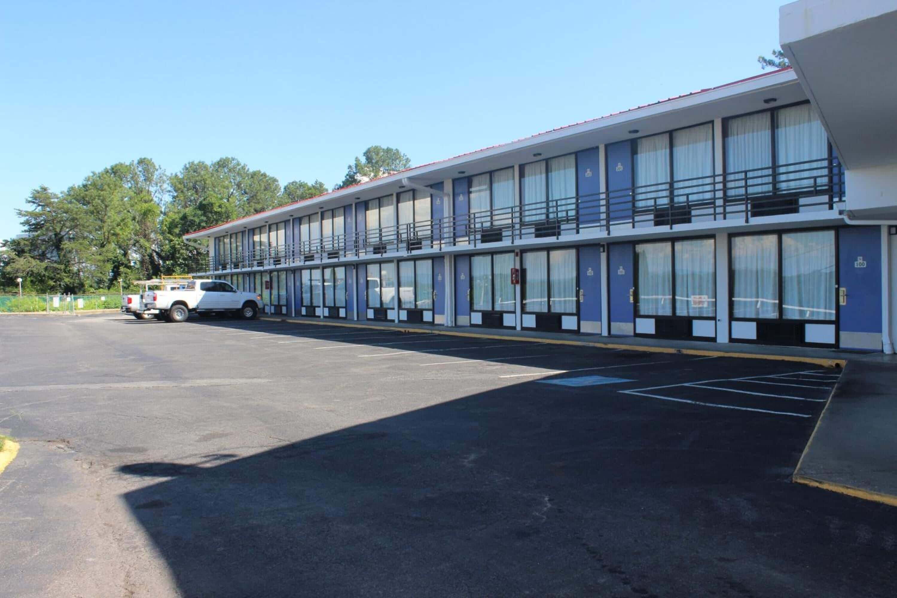 A motel with a row of rooms, a parking lot, and a white truck parked in front.