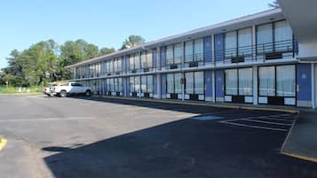 A motel with a row of rooms, a parking lot, and a white truck parked in front.