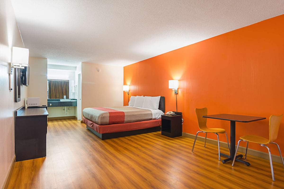 A hotel room with a bed, a desk, a table, and two chairs.
