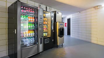 En række automater i en gang med flisegulv og beton gulv.