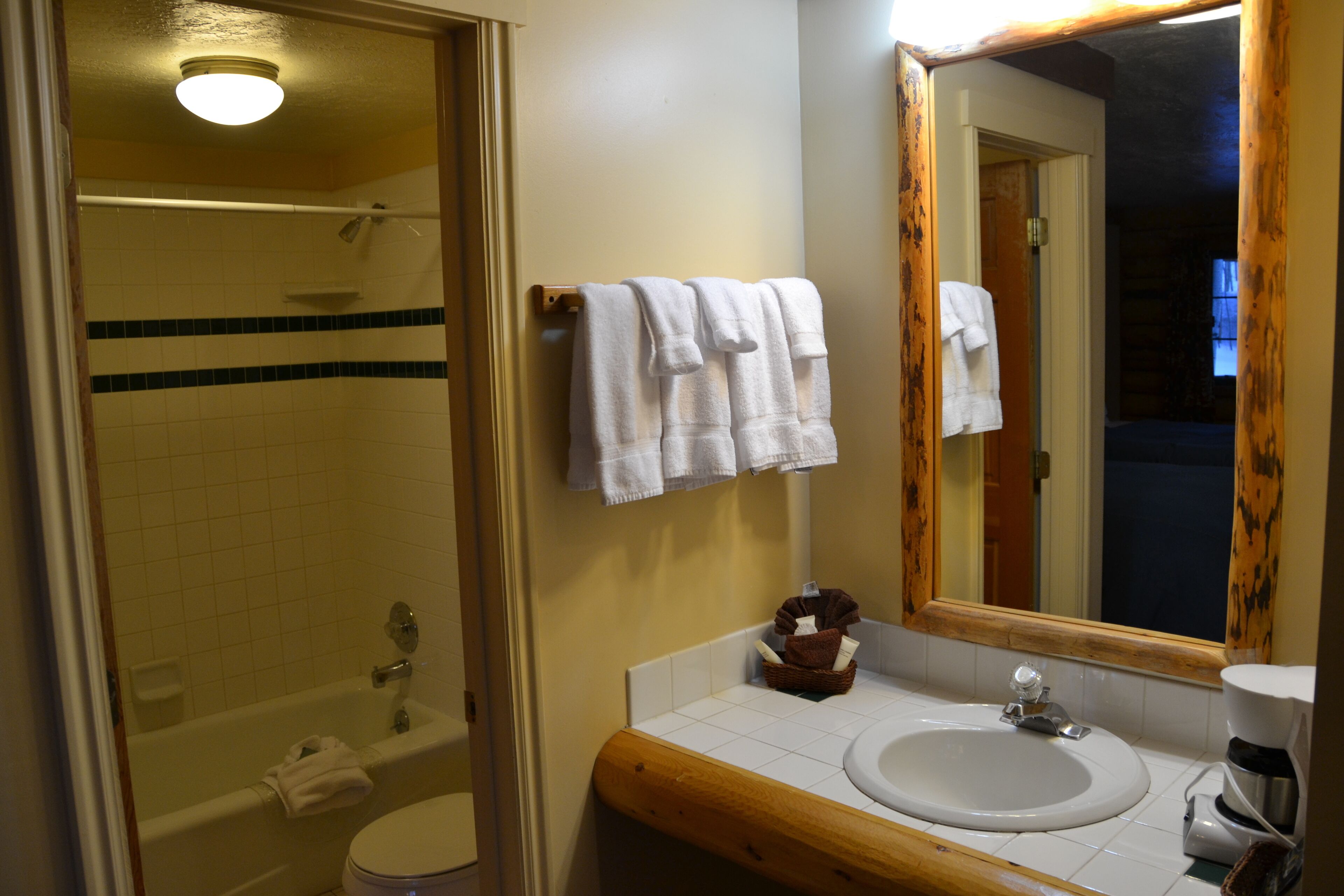 Et badeværelse med badekar, toilet, vask og et spejl.