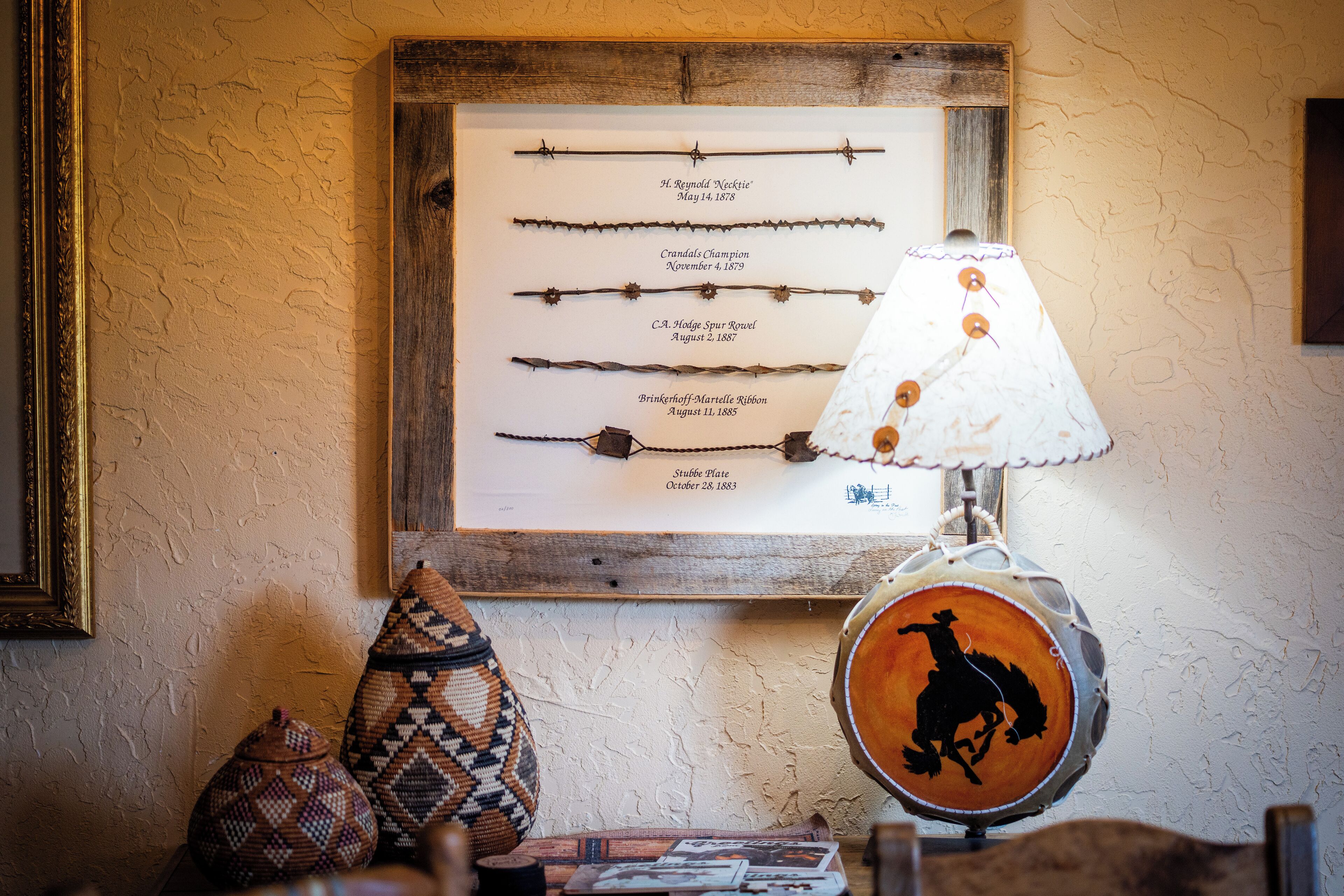 Une collection d’objets variés présentés dans un cadre, avec des dates, une lampe ornée de la silhouette d’un cowboy et des paniers tressés.