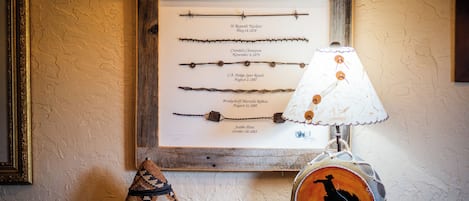 Une collection d’objets variés présentés dans un cadre, avec des dates, une lampe ornée de la silhouette d’un cowboy et des paniers tressés.