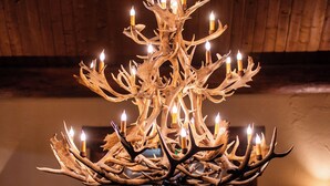 Ein Chandelier aus Geweihen mit Kerzen, platziert in einem Holzkamin mit sichtbarem Flur.