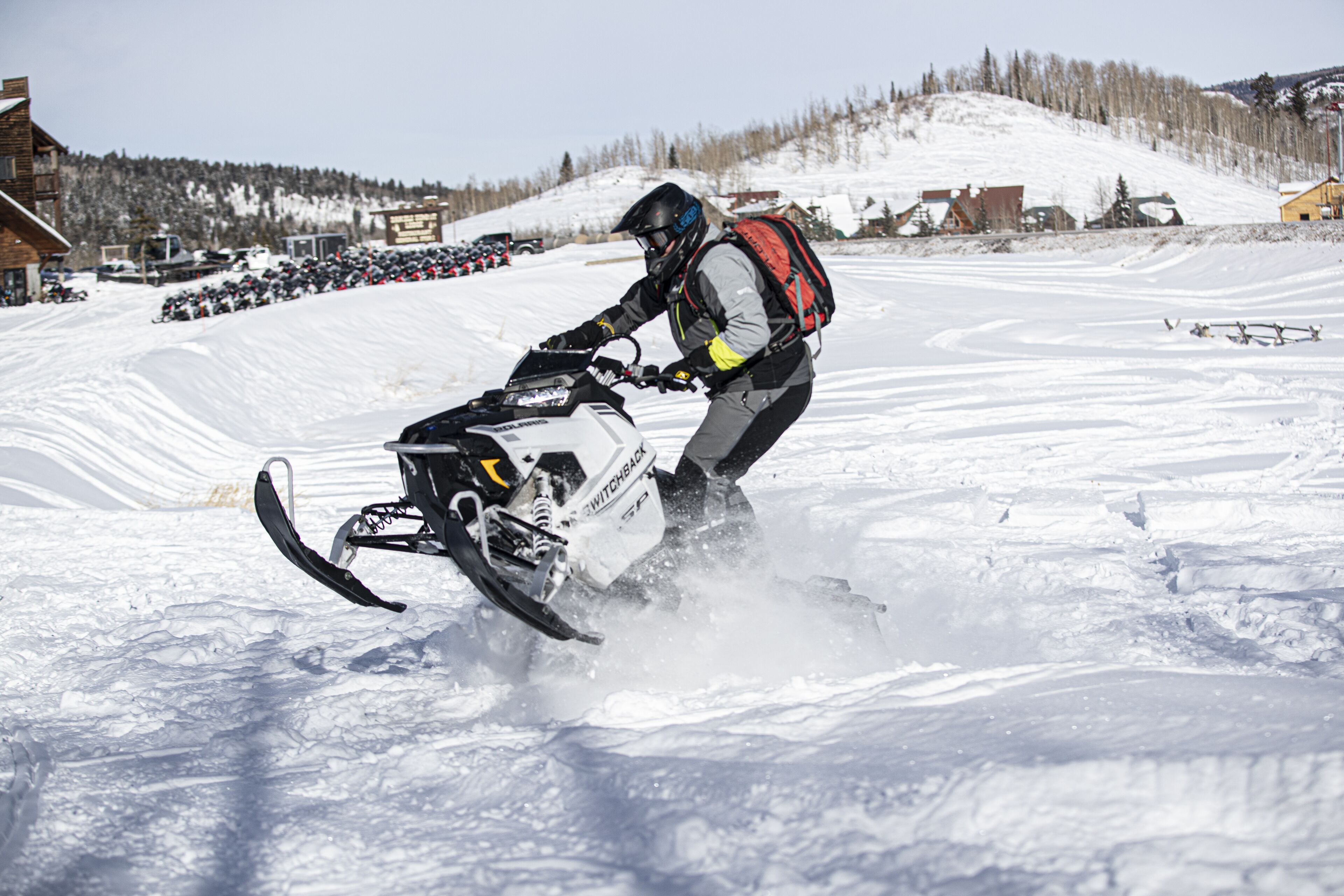 A snowmobile on a snowy slope with a person riding it.