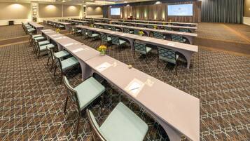 A conference room with long tables, chairs, and a presentation screen.