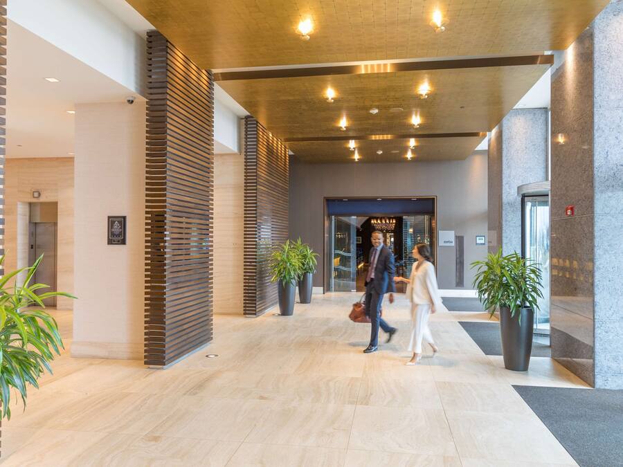 Un hall d'entrée moderne avec un mur à lattes de bois, des plantes en pot et un sol en marbre.