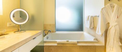 A modern bathroom with a bathtub, a round mirror, and a towel rack.