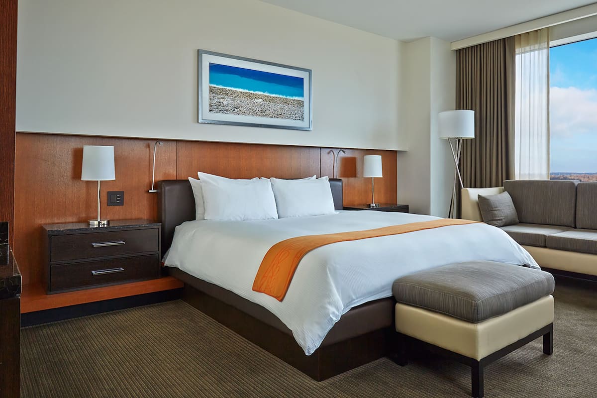 A hotel room with a large bed, a sofa, a desk, and a window with a view.