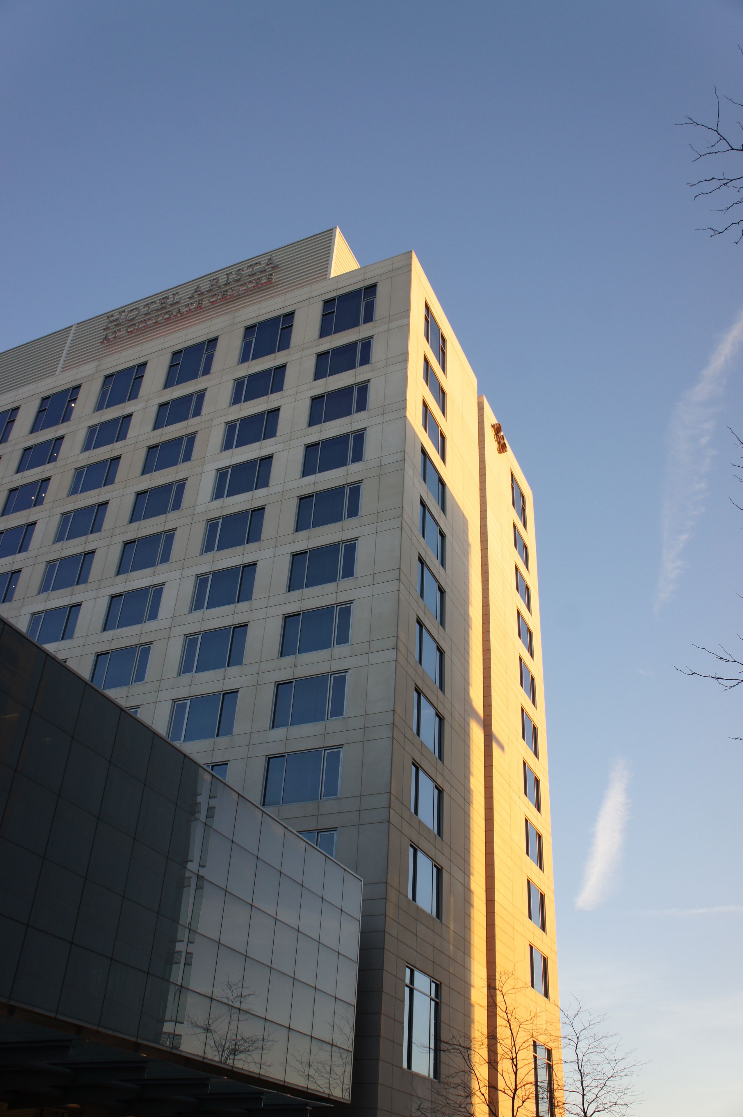 A modern high-rise building with a reflective glass facade and multiple windows.