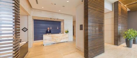 A modern reception area with a marble counter, wooden slatted walls, and a clean, tiled floor.