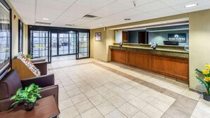 A reception area with a counter, seating, and a view of the parking lot. - Welcome Suites (O'Fallon)