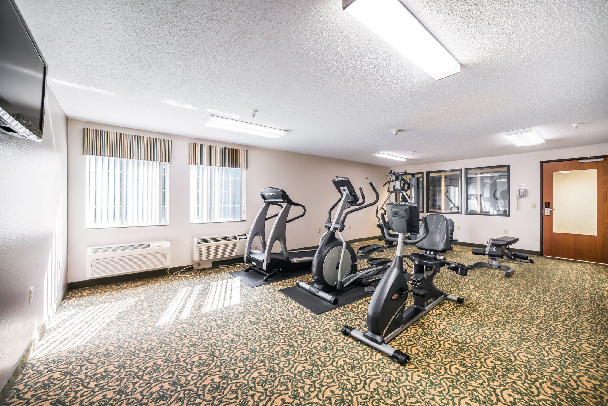 Ein Fitnessstudio mit Laufbändern, Crosstrainern und Ergometer.