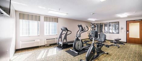 Une salle de sport équipée de tapis de course, d’appareils elliptiques et de vélos d’appartement.