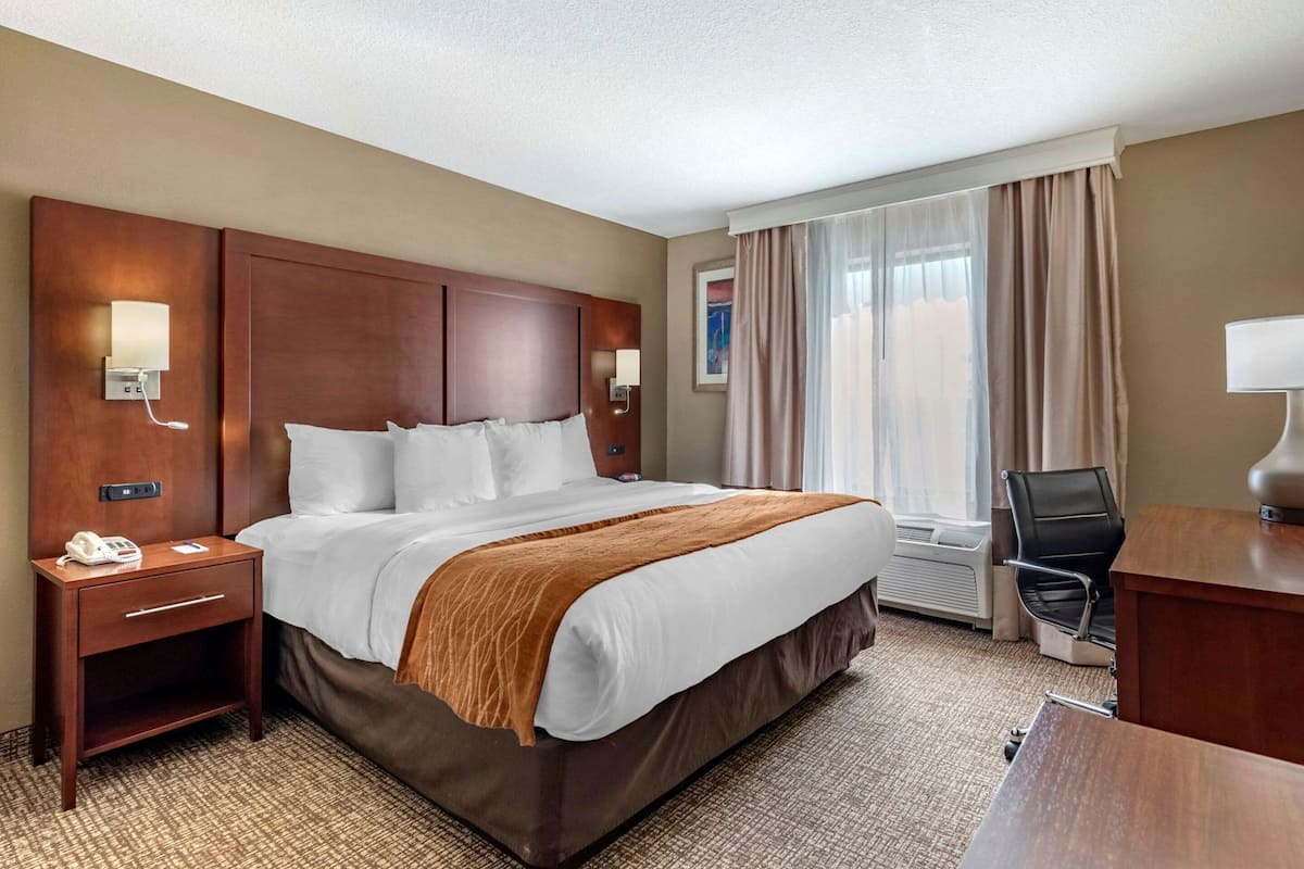 A hotel room with a large bed, bedside tables, a desk, and a chair.