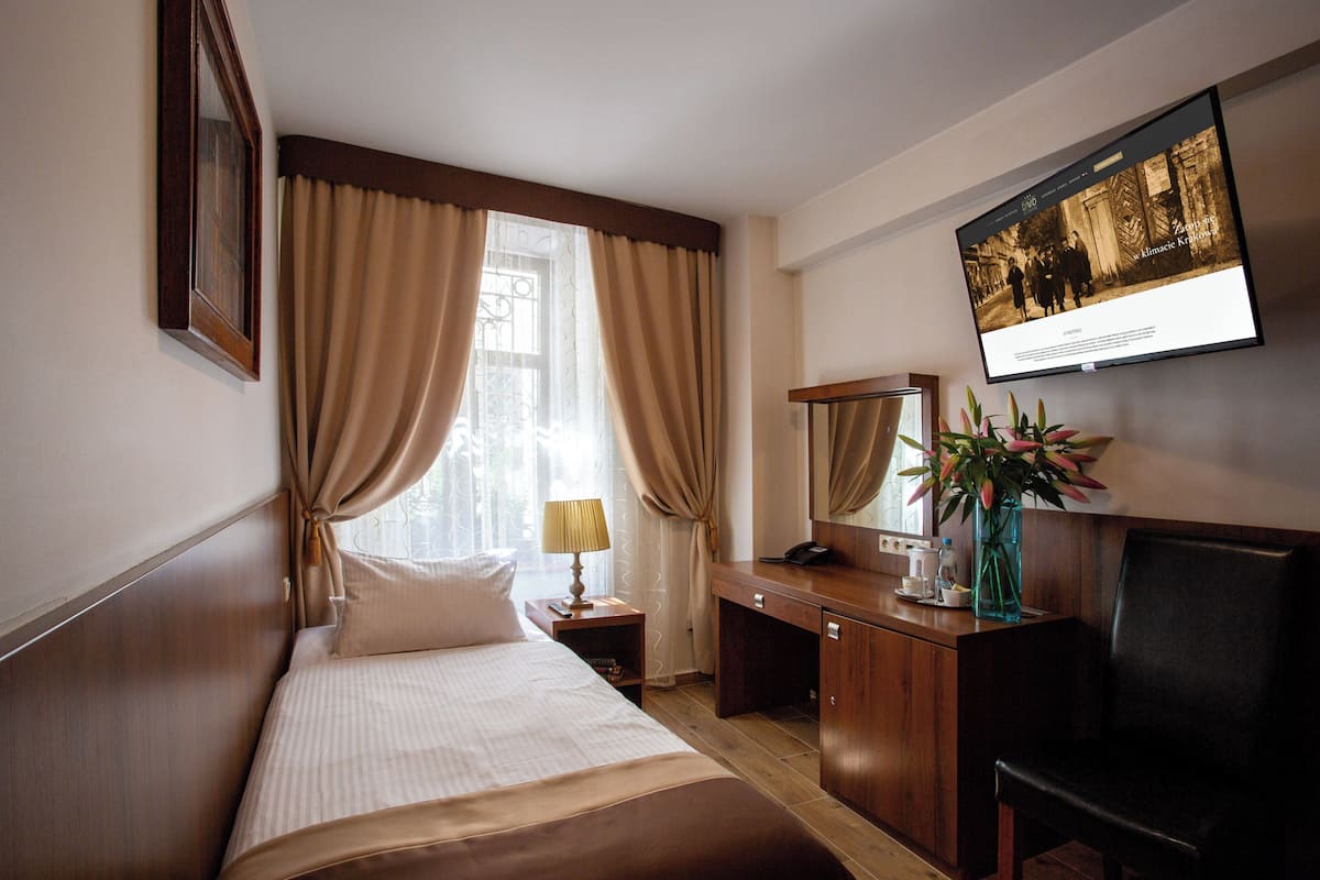 A hotel room with a bed, a desk, a chair, a TV, and a window with curtains.