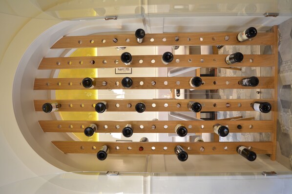A wine rack with multiple bottles in a well-lit room with a tiled floor.