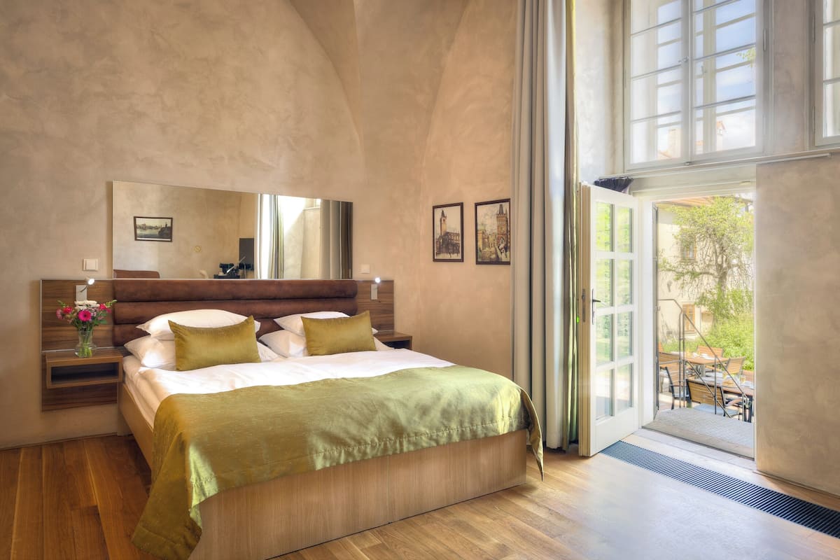 Quarto com uma cama grande, uma mesa de cabeceira, um espelho e vista para o exterior através de uma porta deslizante.