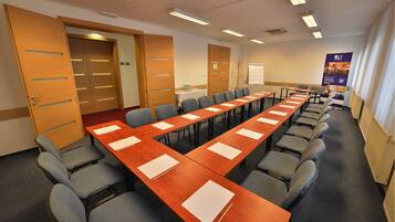 A conference room with a long table, chairs, and a whiteboard.