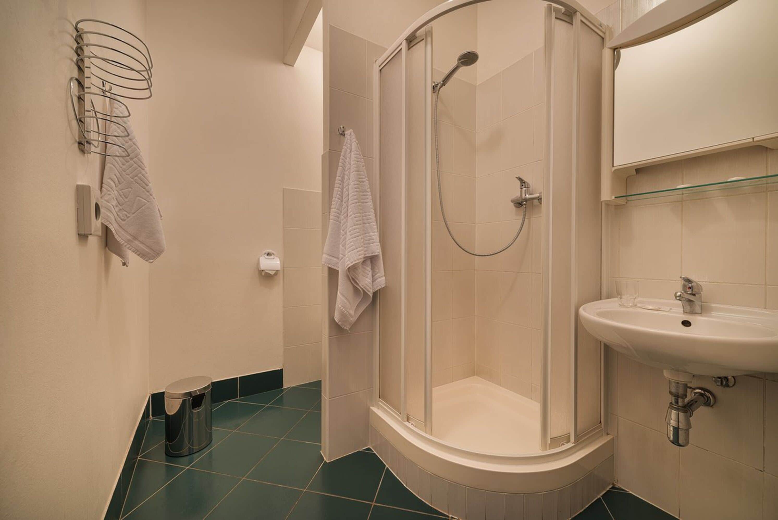 A bathroom with a shower, sink, and towel rack.