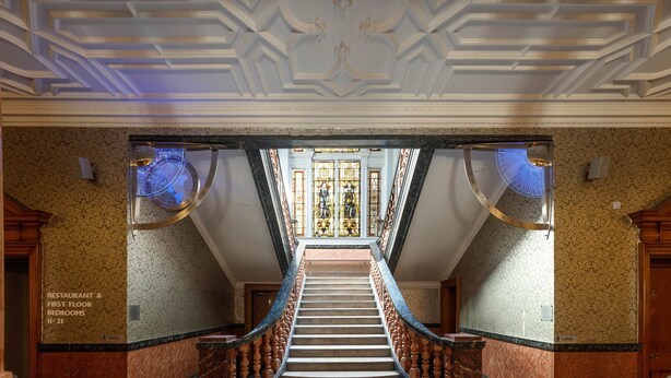 A grand staircase with ornate railings and a patterned floor, leading to a room with a large stained glass window. - Cathedral Quarter Hotel - Derby (Derby)
