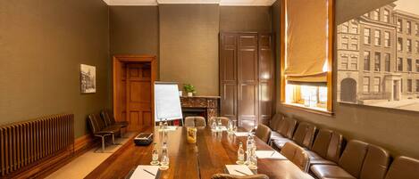 Uma sala de conferências com uma mesa comprida, cadeiras de couro, um quadro branco e vista para a cidade.