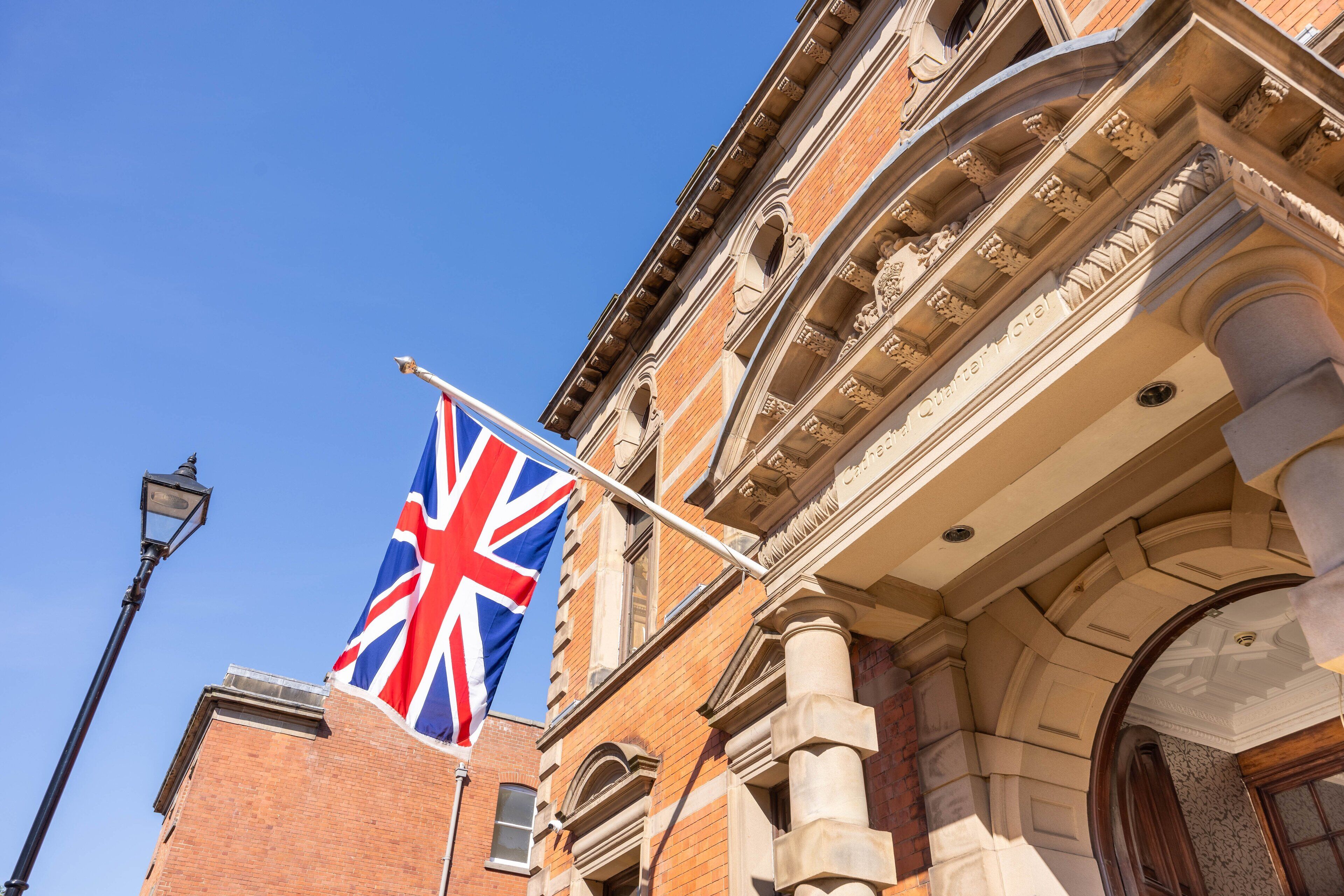 A building with a British flag, classical architecture, and a street lamp.