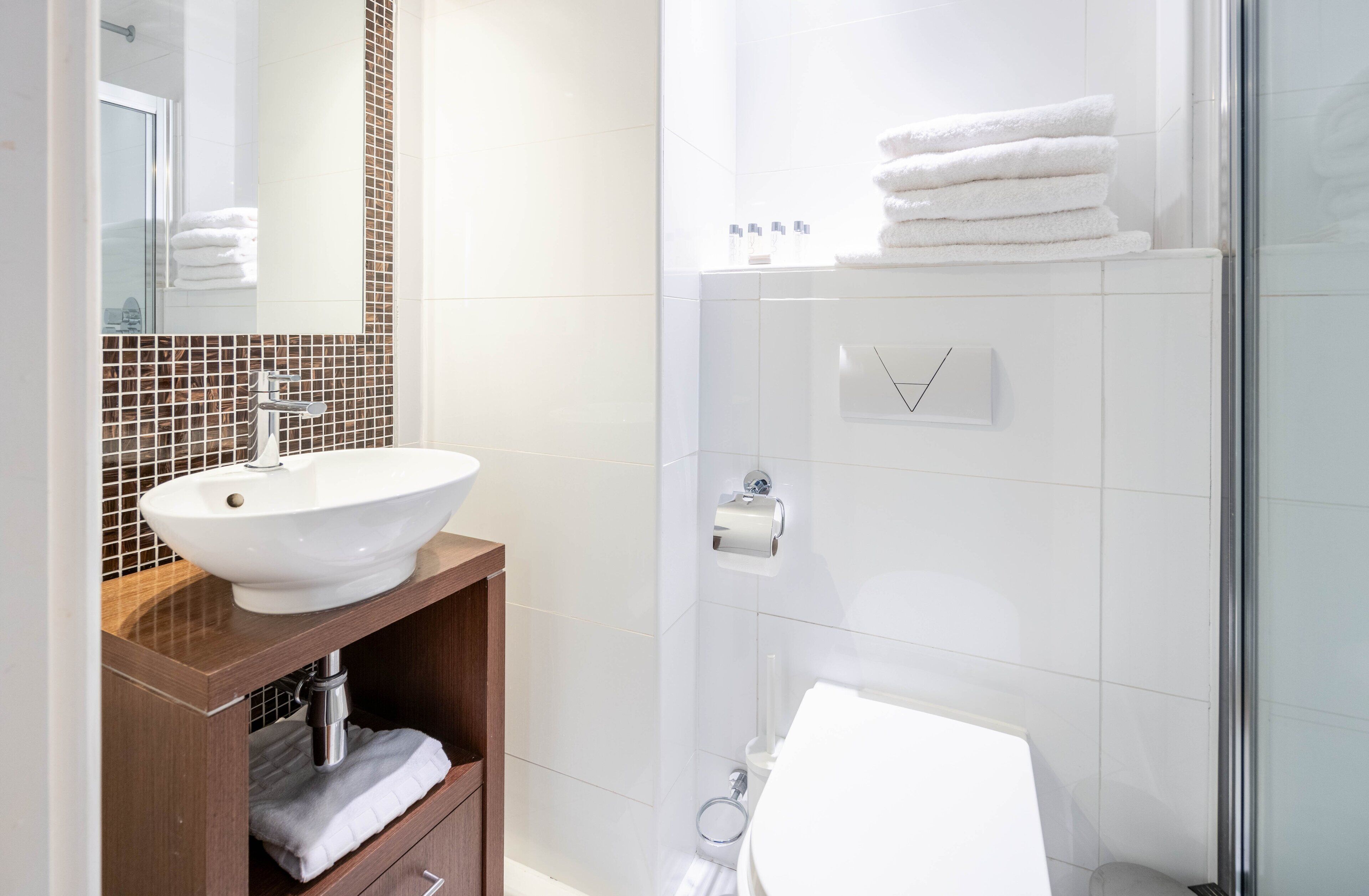 A modern bathroom with a white sink, mirror, and shower.