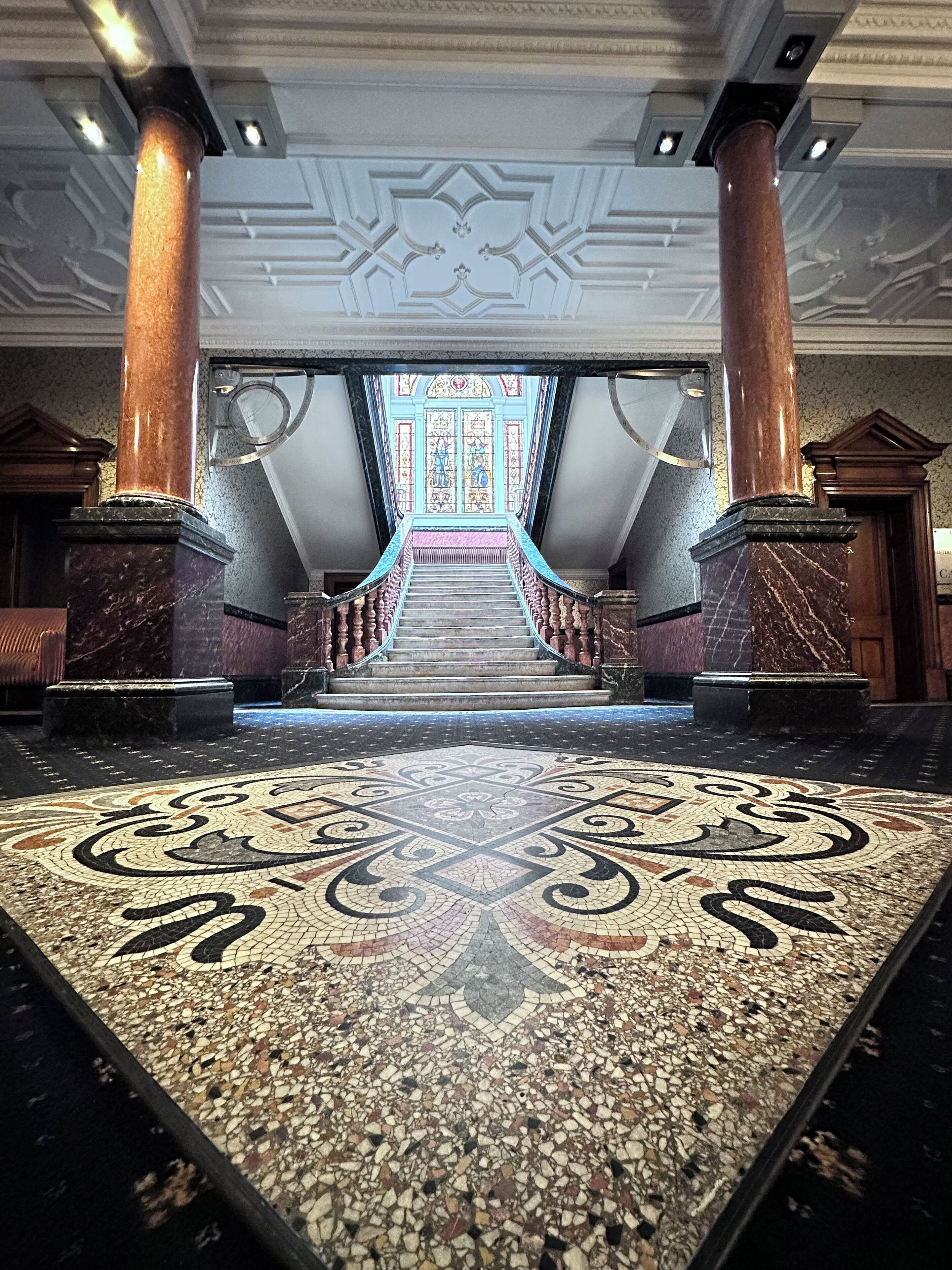 A grand staircase with a mosaic floor leading to a large, ornate door.