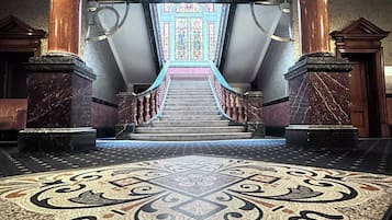 A grand staircase with a mosaic floor leading to a large, ornate door.