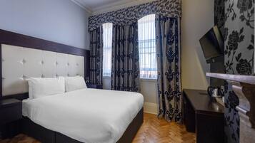 Een slaapkamer met een groot bed, een hoofdbord, een nachtkastje, een bureau en een televisie.