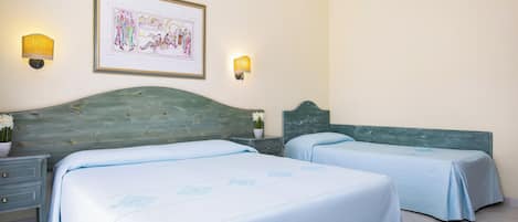 Een hotelkamer met twee bedden, een nachtkastje, een ingelijste foto en wandlampen.