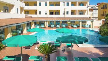 Een hotel met een zwembad, buiten zitplaatsen en een overdekt terras.