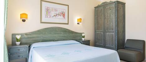 A bedroom with a bed, nightstands, a lamp, a cabinet, and a chair.