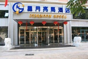 The exterior of the Star Moon Hotel with a modern facade, large glass entrance, and traditional red lanterns. - Starmoon Hotel (Beijing)